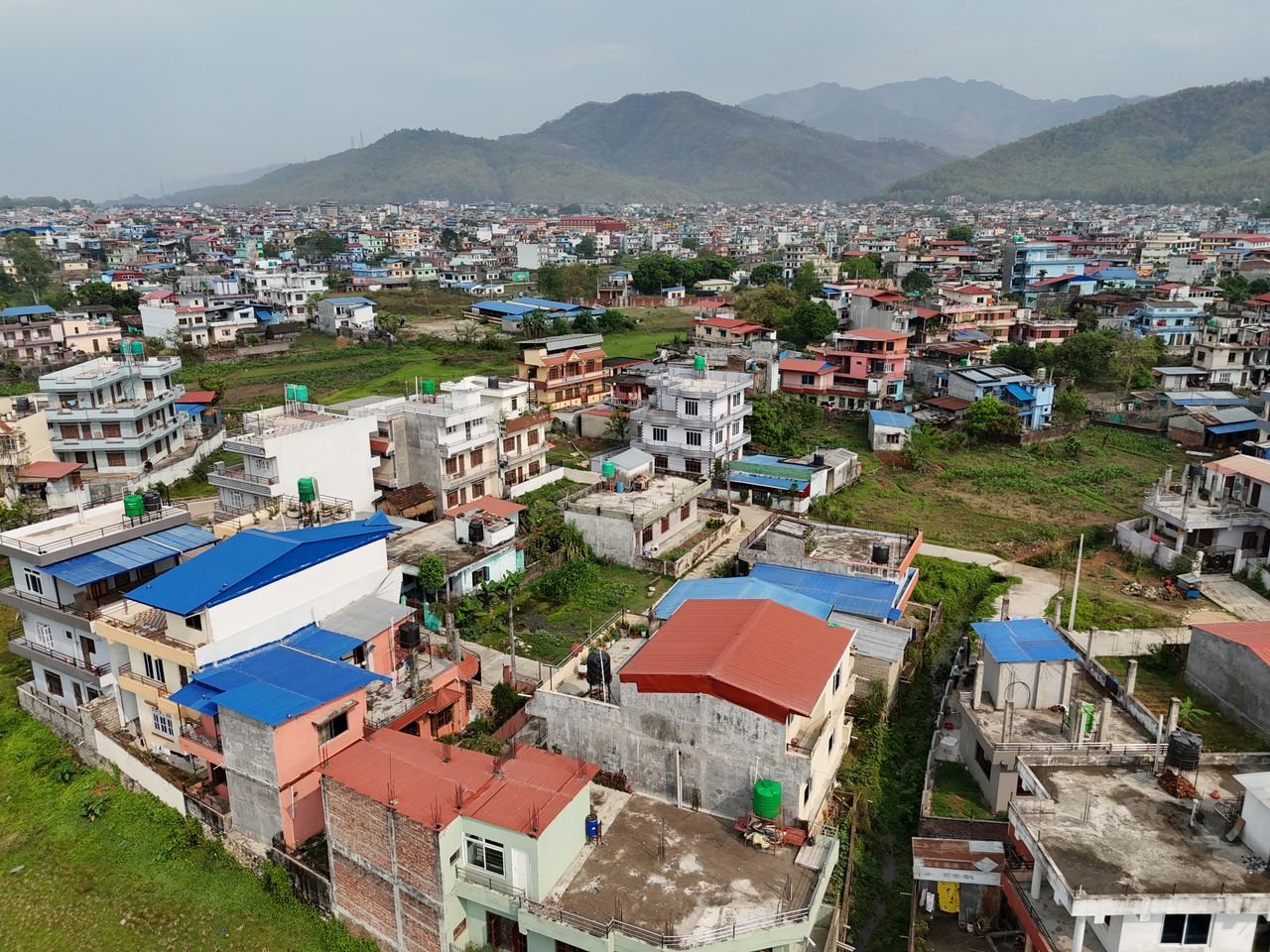 Aerial shot of residential areas and distant mountains in Nepal, showcasing urban landscape.